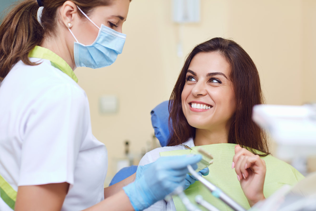 Teeth whitening dental clinic. Closeup of a young woman with beautiful smile at the dentist.