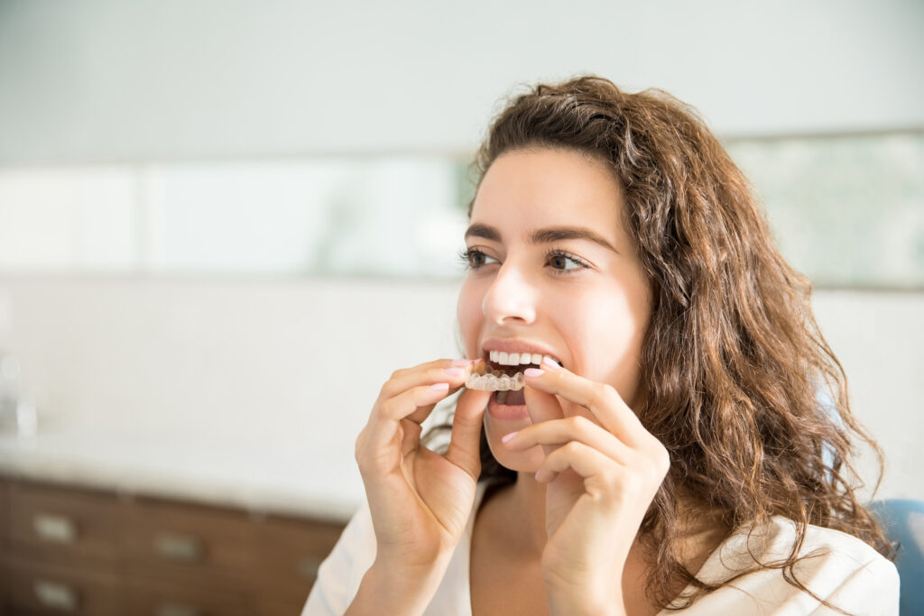 Closeup of beautiful young woman wearing clear aligner in dental clinic