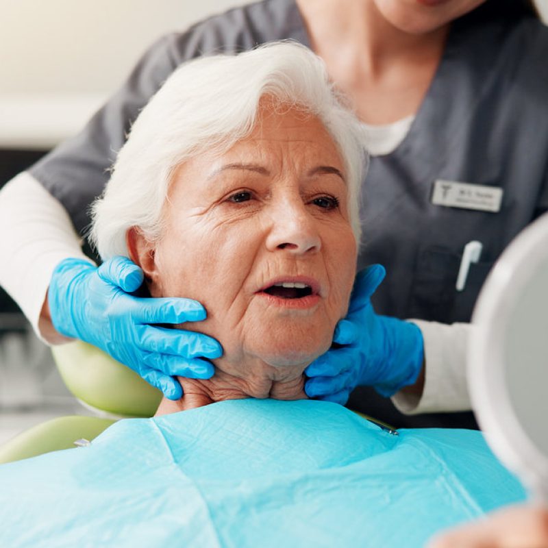 Dental, senior woman and mirror with results for teeth whitening, gum disease and dentures. Pensioner, healthcare and dentist with elderly patient in clinic for cavity removal or root canal treatment.